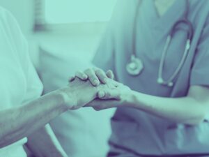 Photo of compassionate nurse holding seniors hand